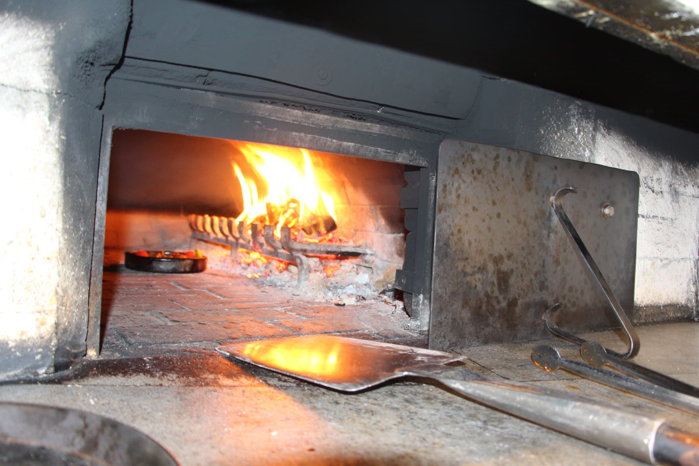 Lehmofen mit brennendem Holz und Ofenschieber